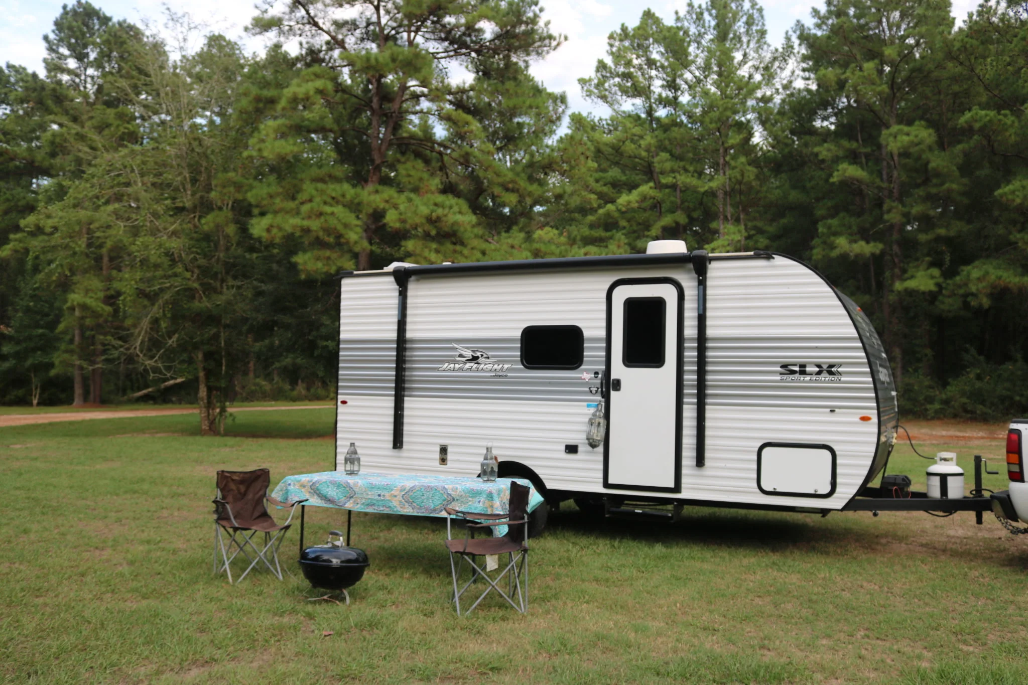The Basecamp set up at a grassy campsite with outdoor chairs, a table and a small grill