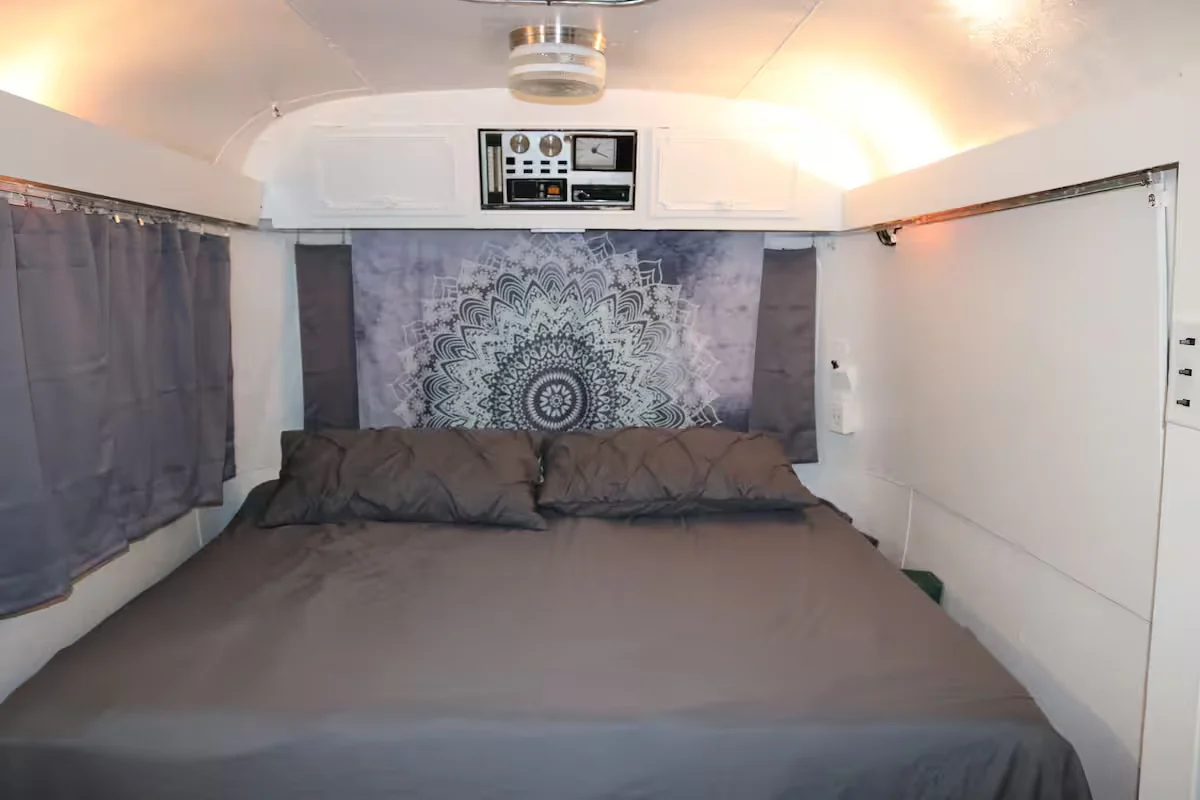 Main sleeping area inside the Avion with a gray bed and patterned wall hanging