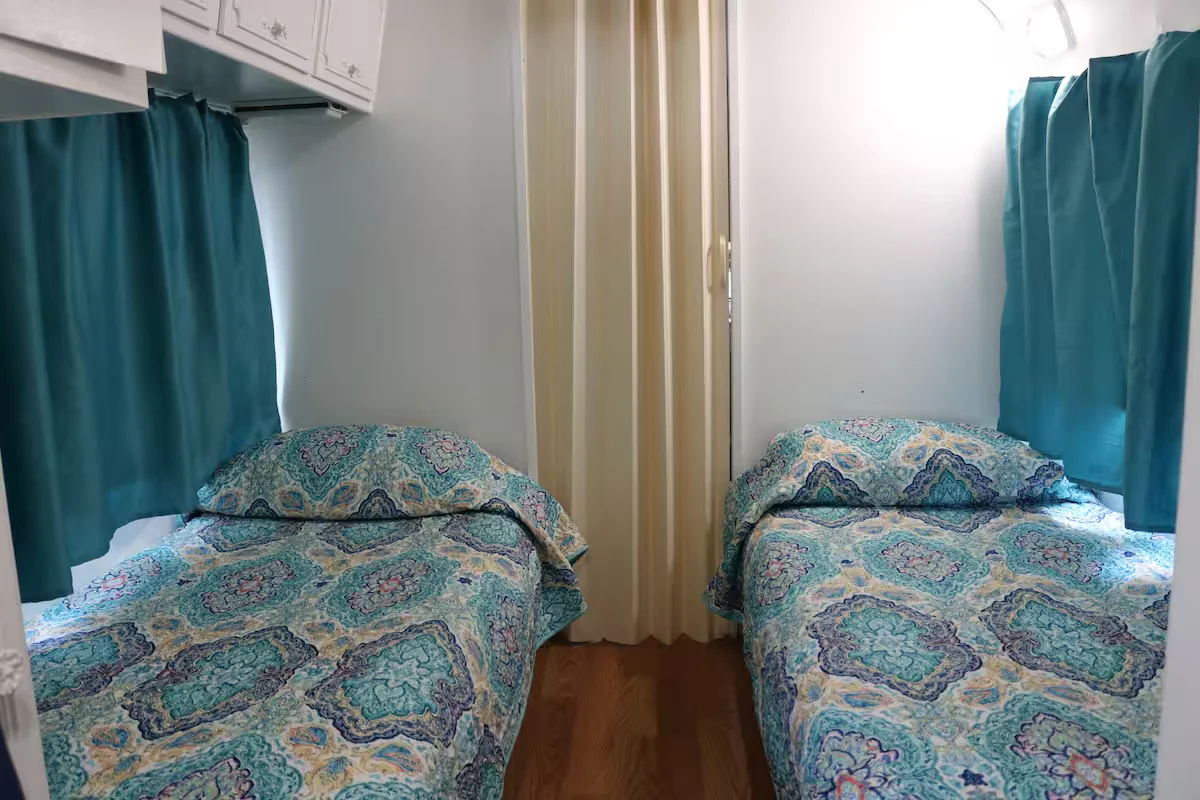 Second sleeping area inside the Avion with two twin beds and turquoise curtains