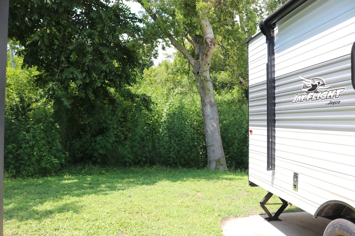 JayCation travel trailer set among trees at the campground